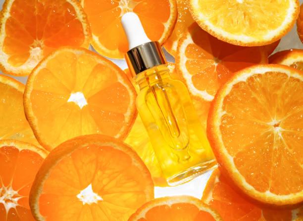 Vitamin C serum dropper bottle on fresh orange slices background